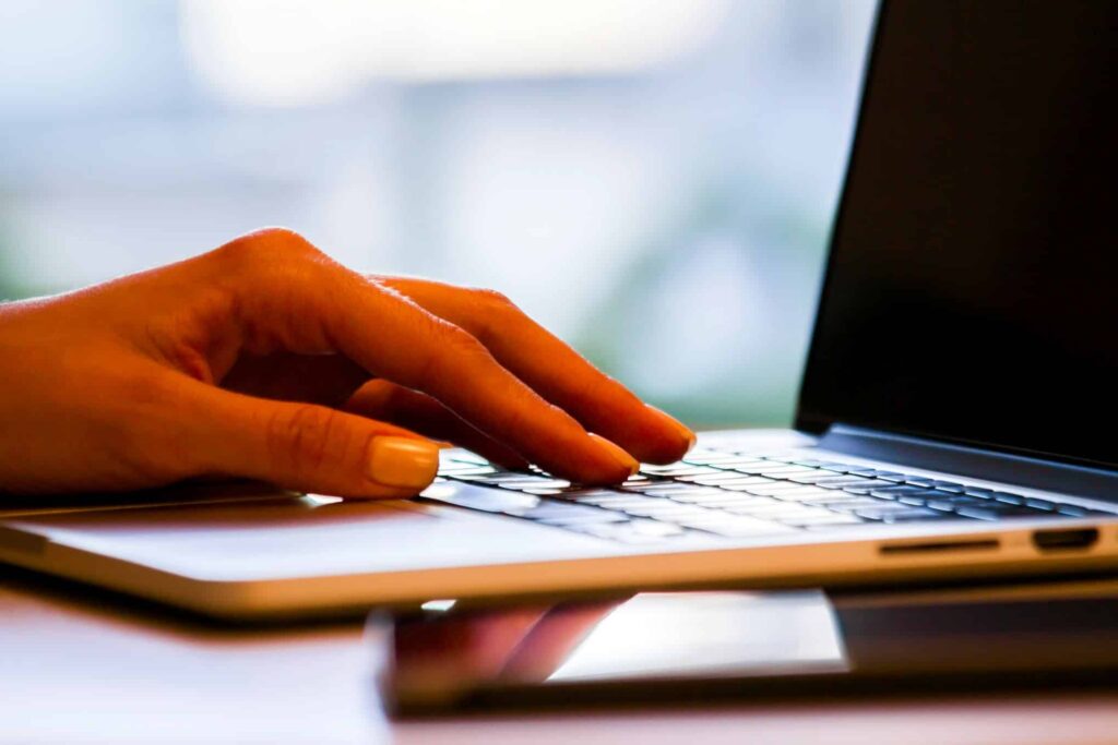 Käsi on kannettavan tietokoneen näppäimistöllä.