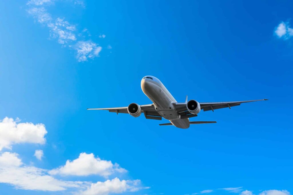 Lentokone, joka lentää. Taustalla sininen taivas ja muutamia poutapilviä.