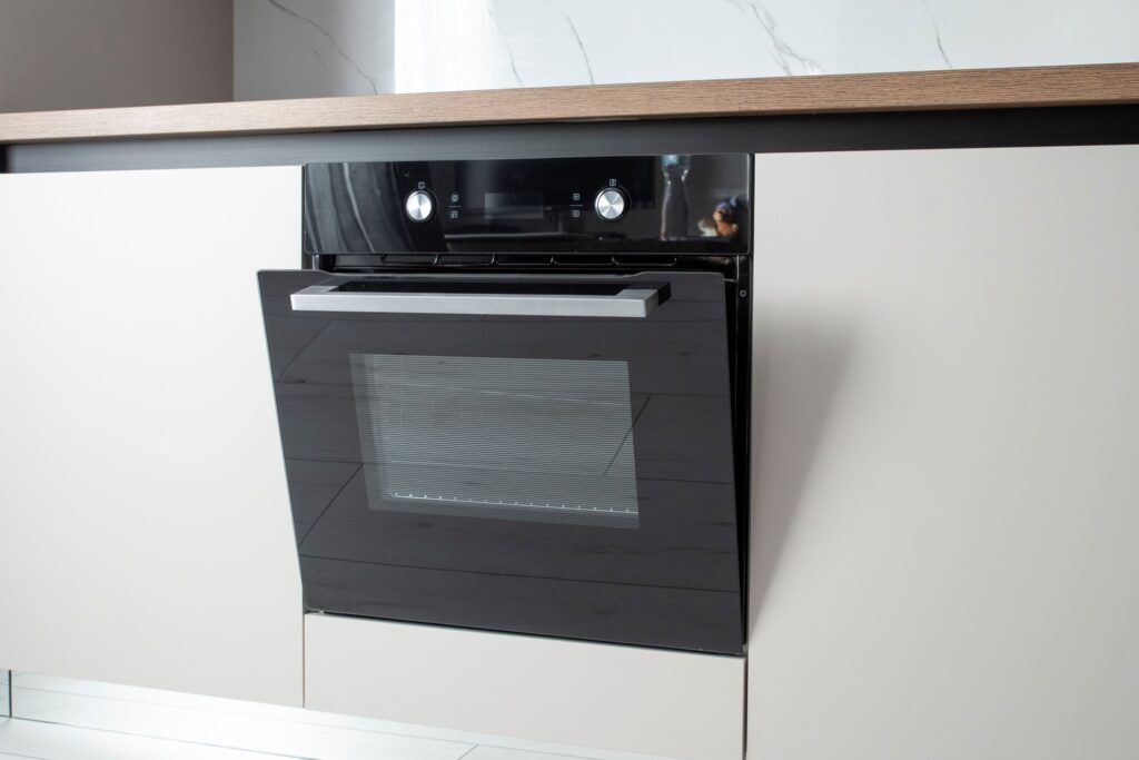 Kalusteisiin asennettu uuni, jonka luukku on raollaan.