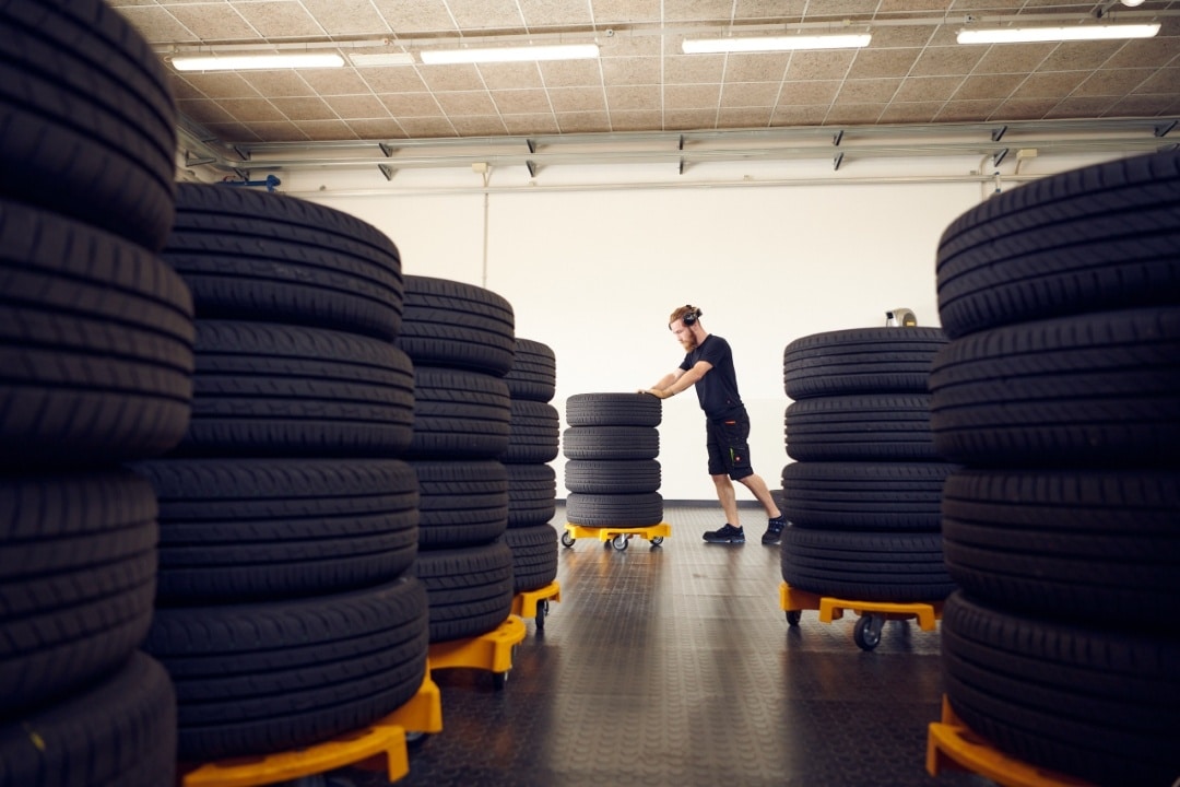 Varastohallissa on useita rengaspinoja sekä henkilö siirtämässä rengaspinoa.