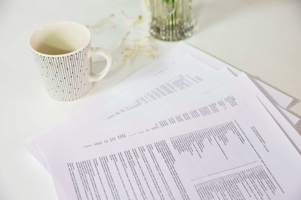 Pöydällä on vakuutusasiakirjoja ja kahvikuppi.