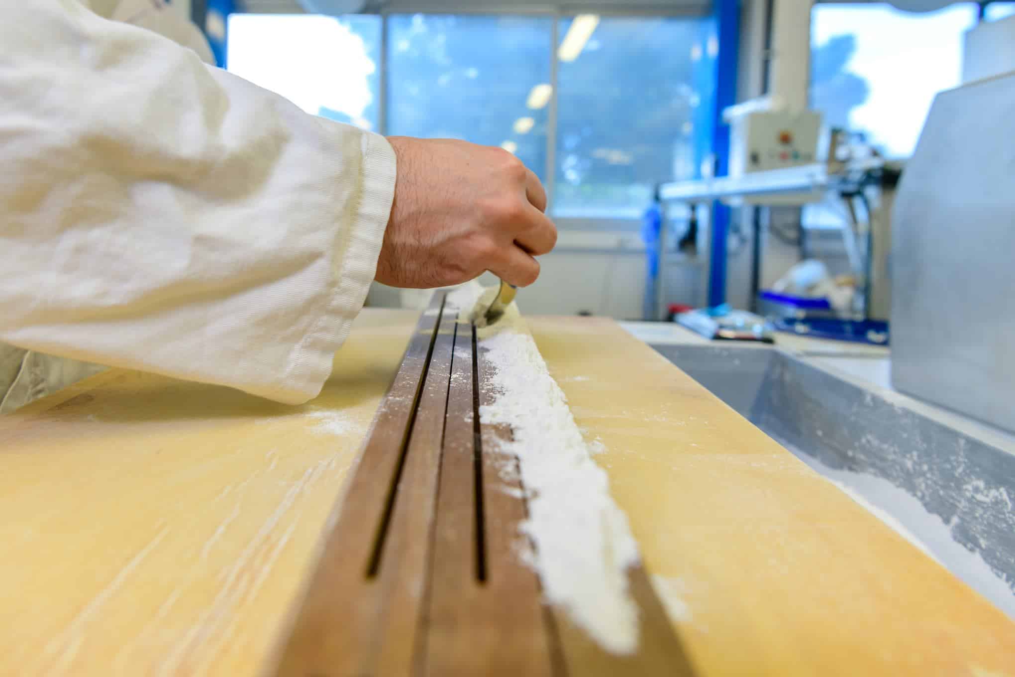 Henkilö levittää dolomiittihiekkapölyä puupinnassa oleviin rakoihin.