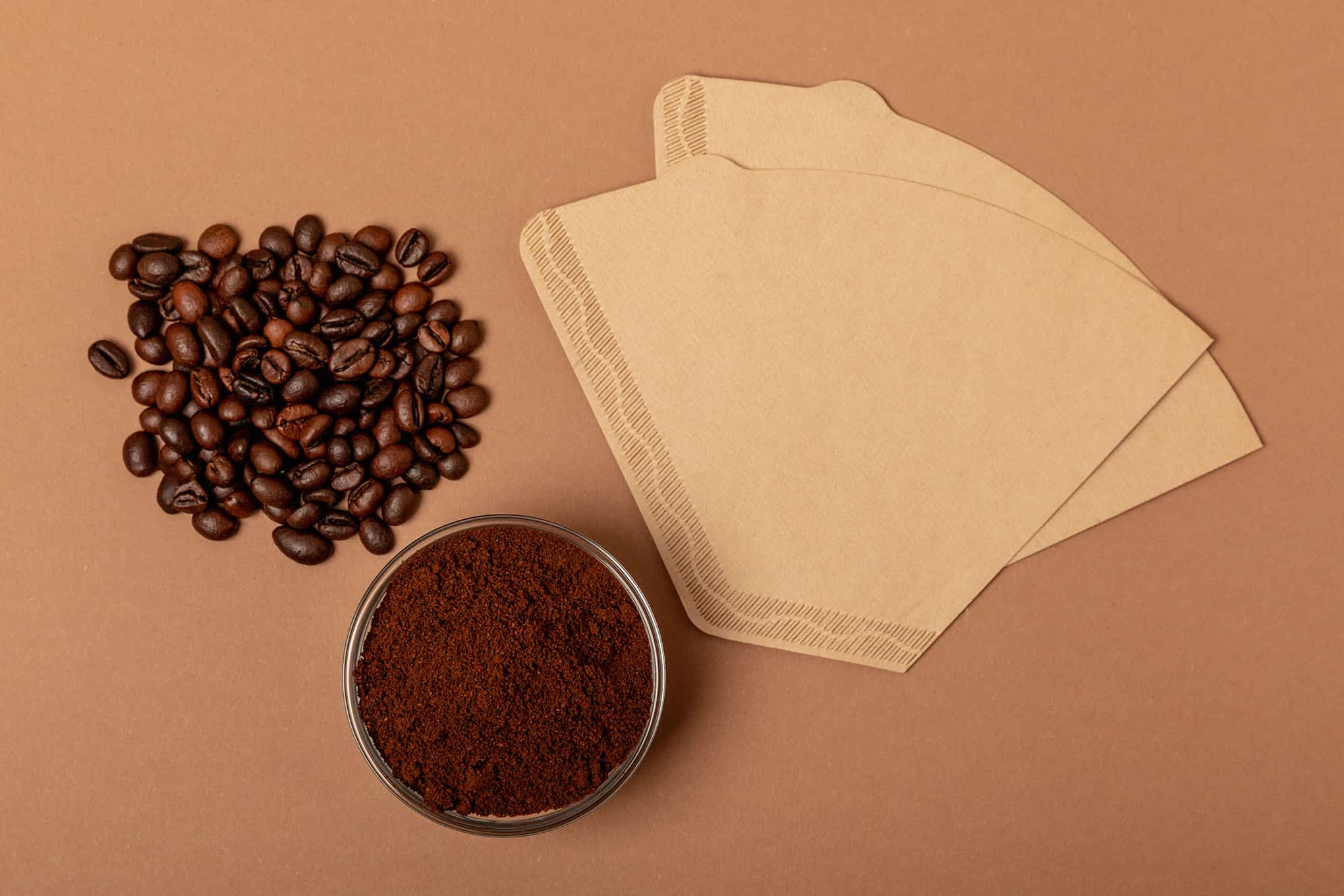 Kahvipapuja, jauhettua kahvia ja kaksi suodatinpussia.