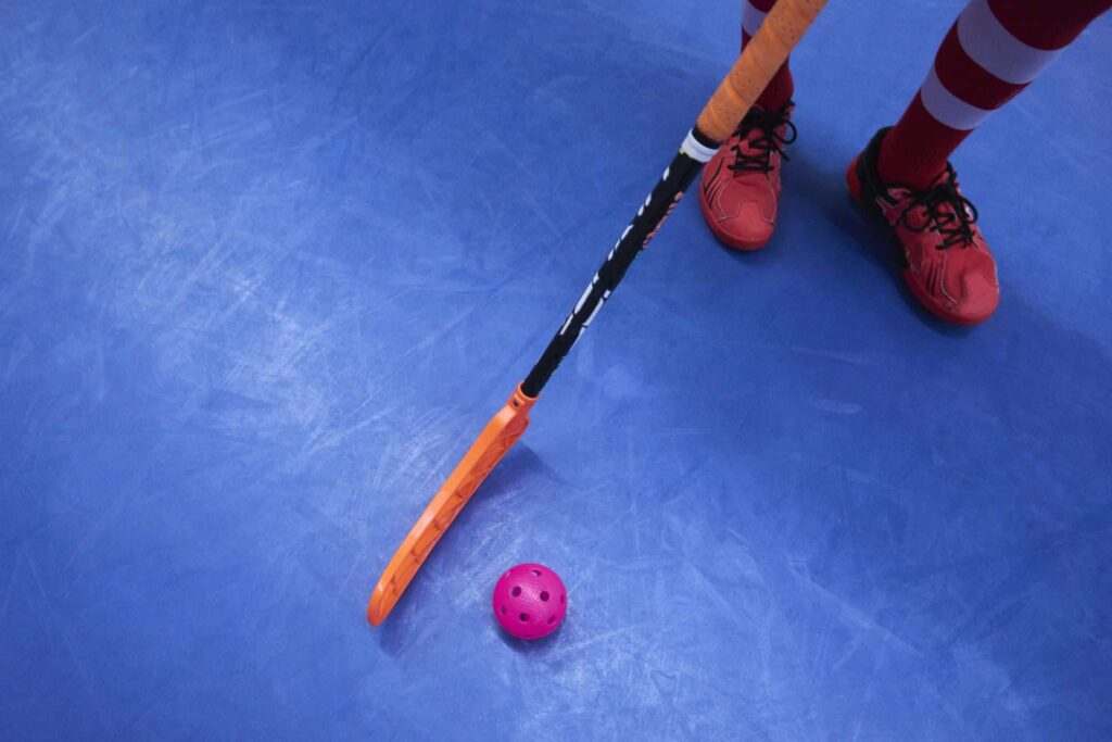 Salibandyn pelaaja, salibandymaila ja salibandypallo.