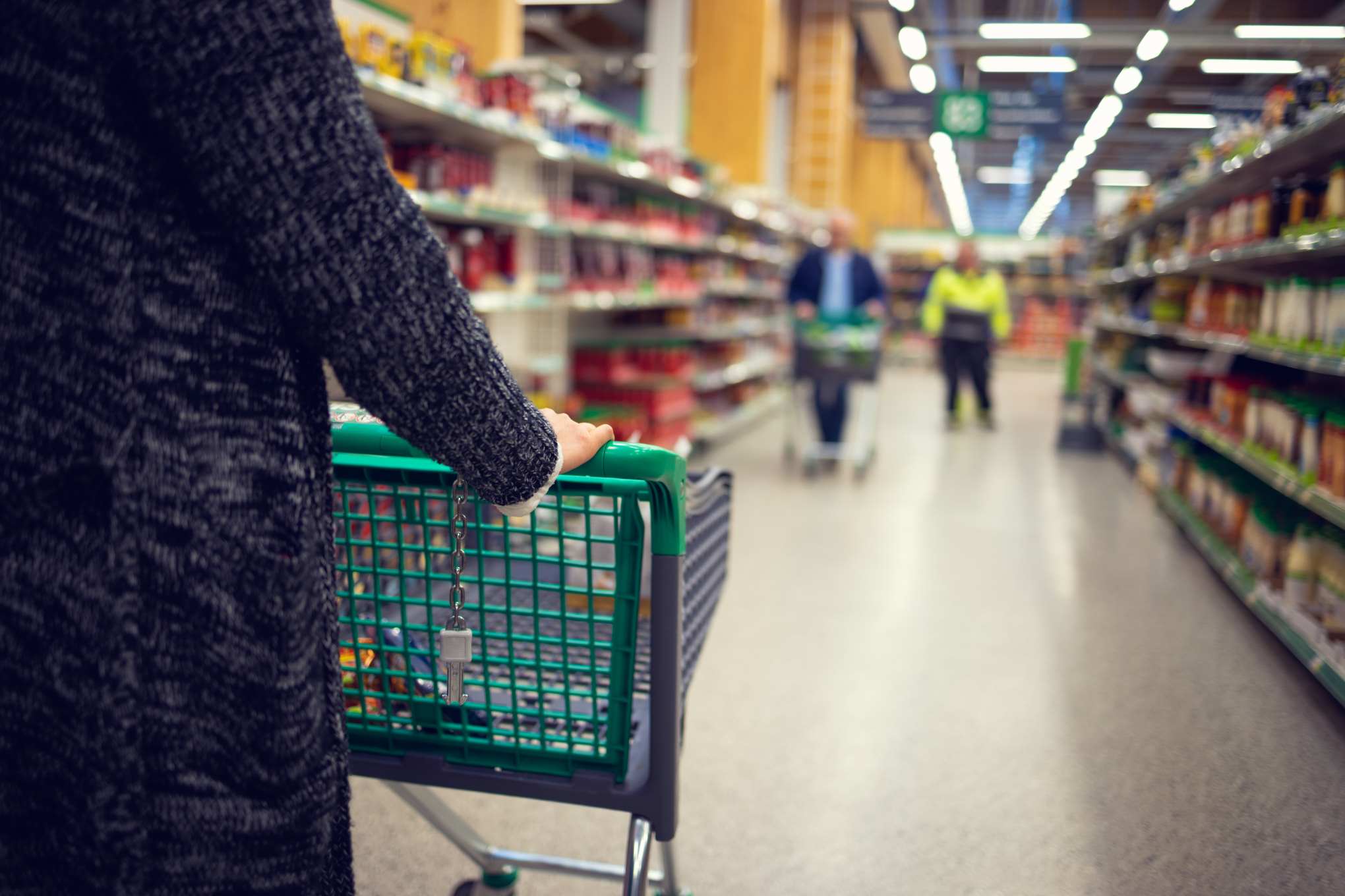 Henkilö työntää ostoskärryjä ruokakaupassa.