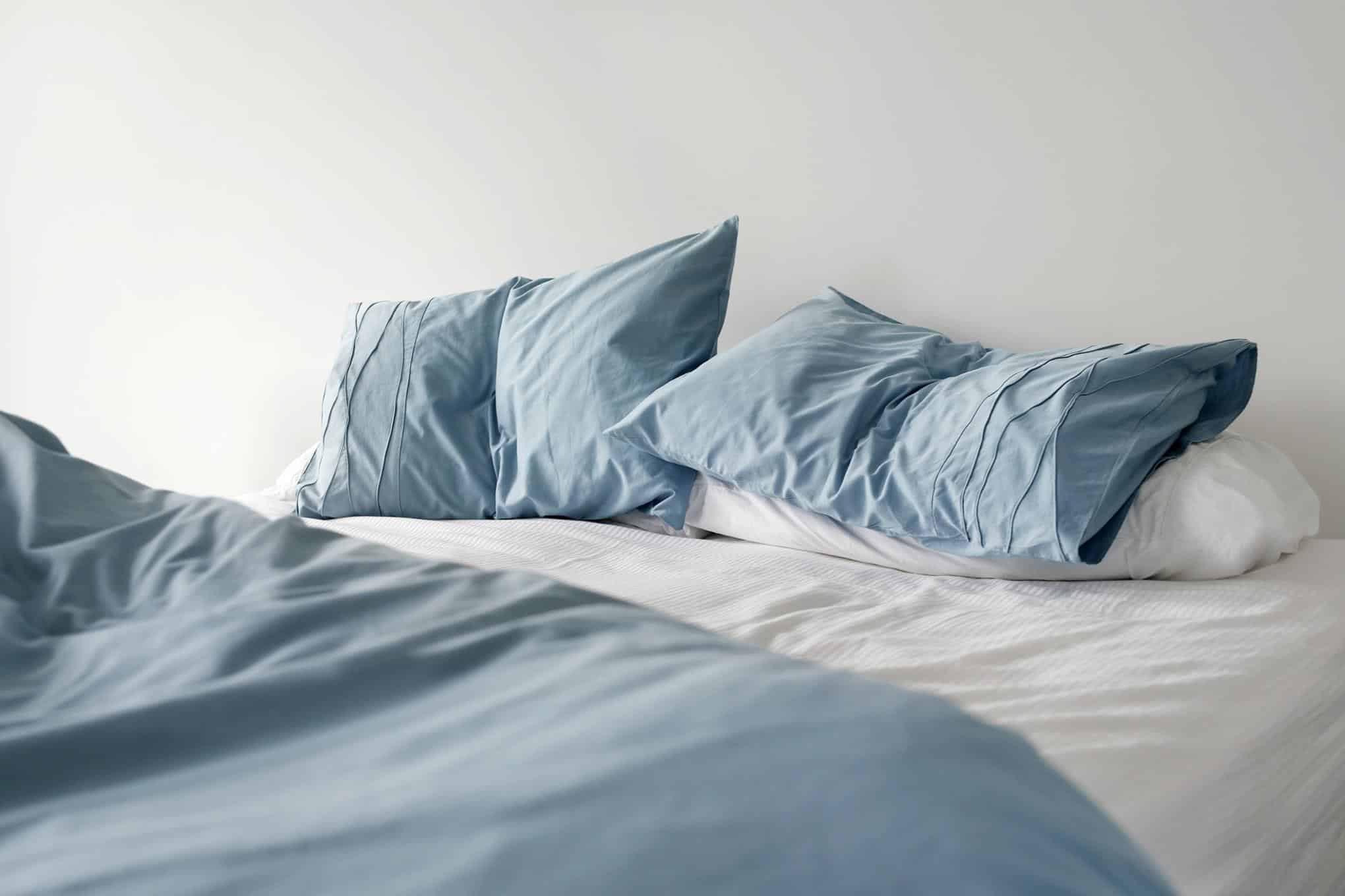 Sänky, jonka päällä on peitto ja tyynyjä.