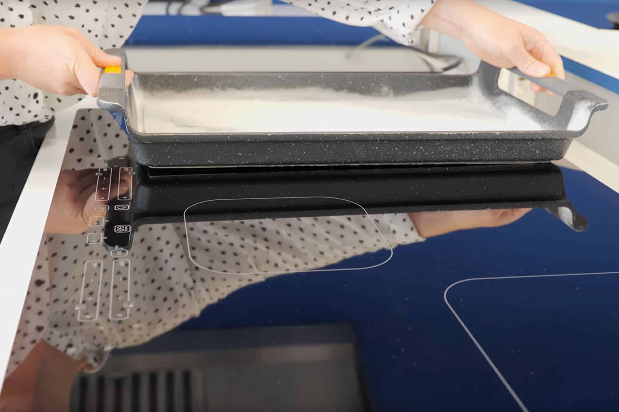 Induktiotaso, jonka päälle henkilö asettaa paistoastiaa.