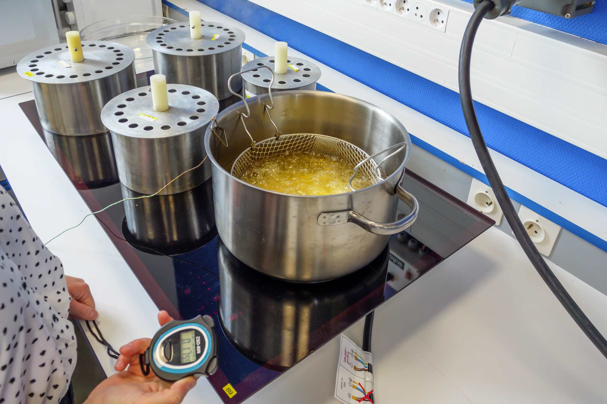 Induktiotaso, jonka päällä on testauslaitteistoa sekä kattila, jossa on öljyä.