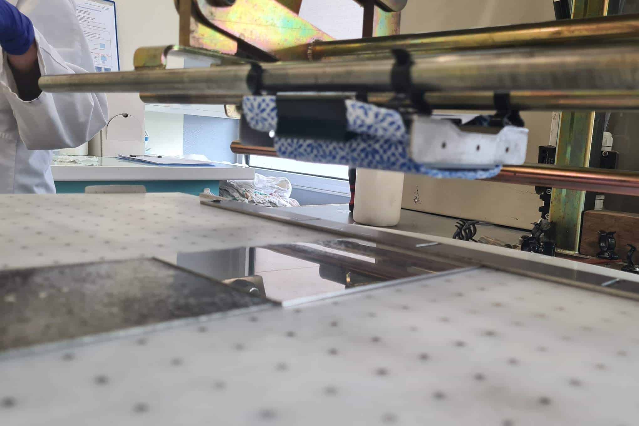 Testauslaitteistoa laboratoriossa sekä henkilö, jolla on kädessään suojahanskat.