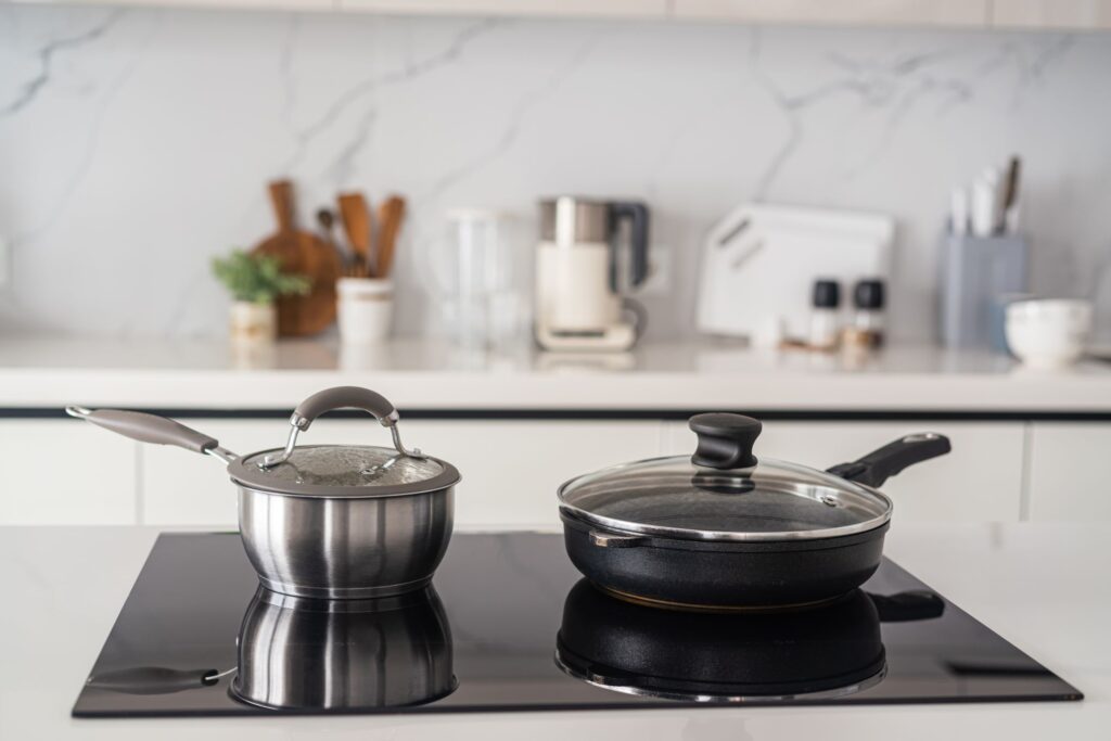 Keittiössä on induktiotaso, jonka päällä on pannu ja kattila.