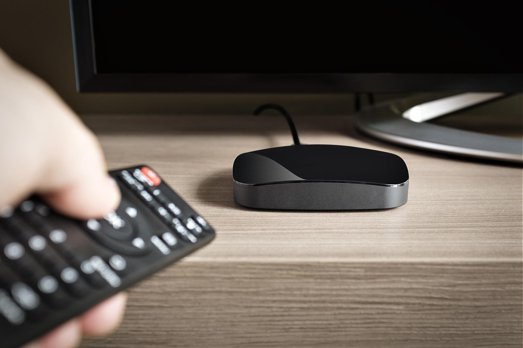 Henkilö osoittaa kaukosäätimellä äly-tv-laitetta.