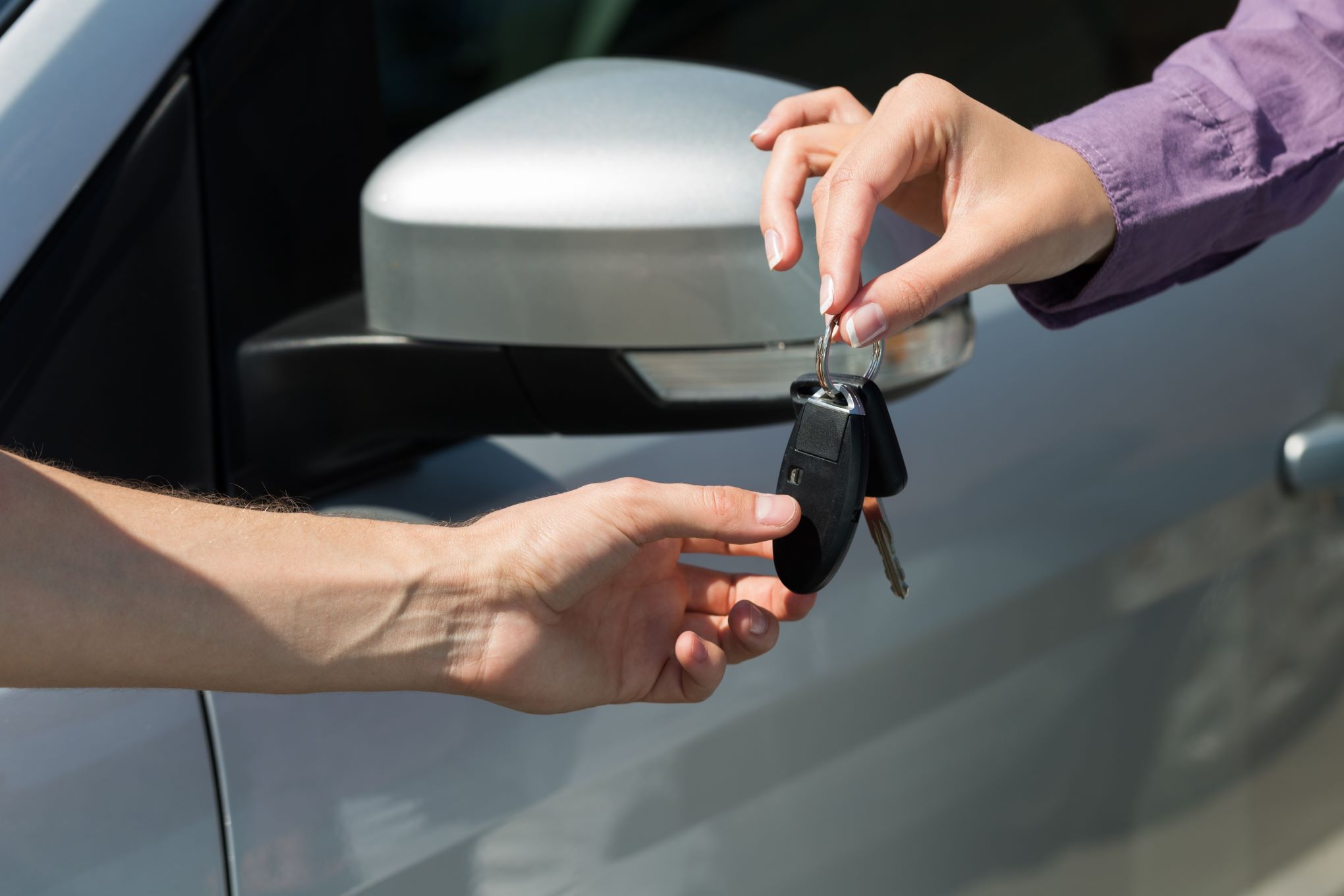 Henkilö antamassa auton avaimia toiselle henkilölle.