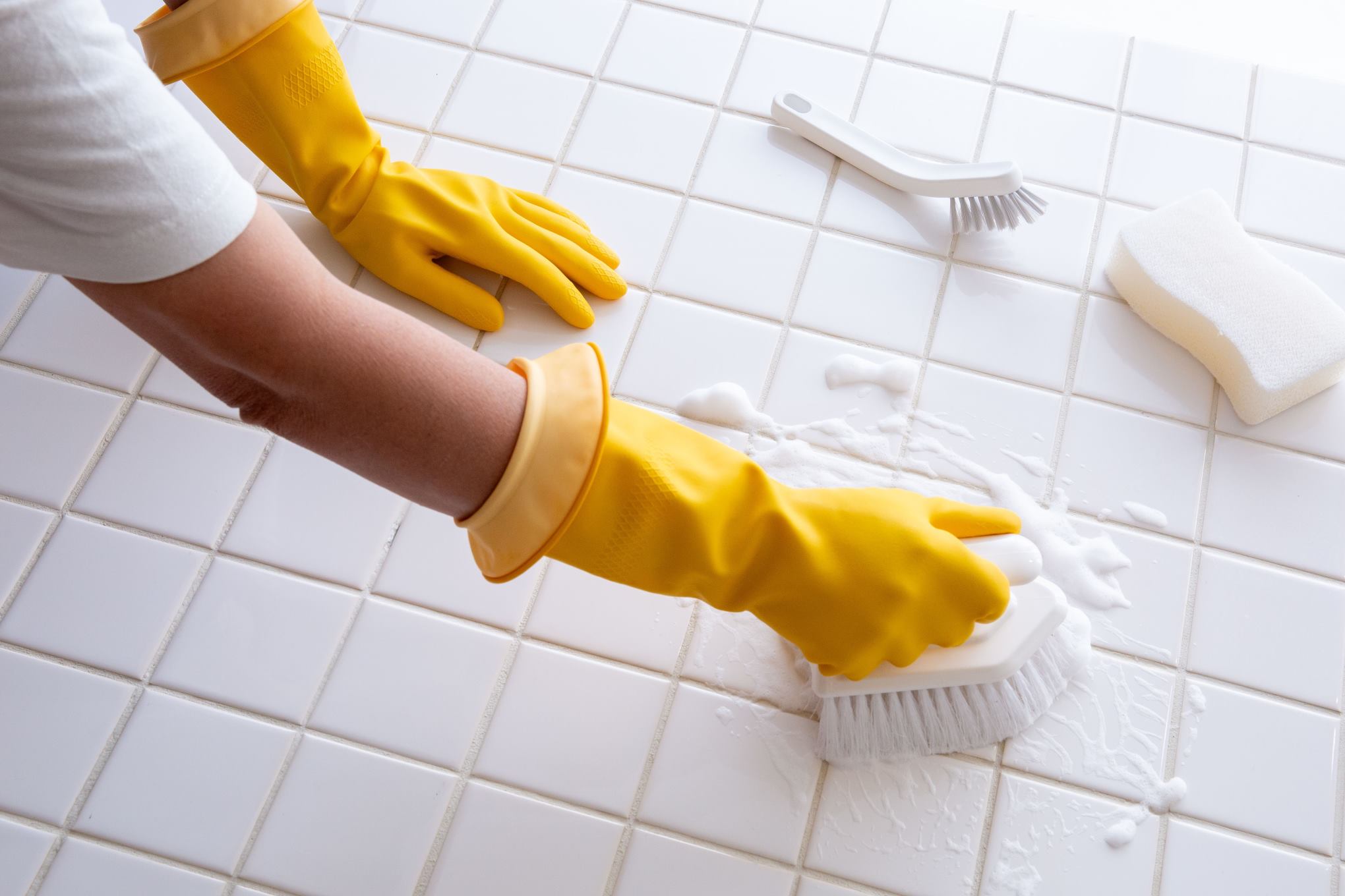 Henkilö siivoamassa kaakelilattiaa.