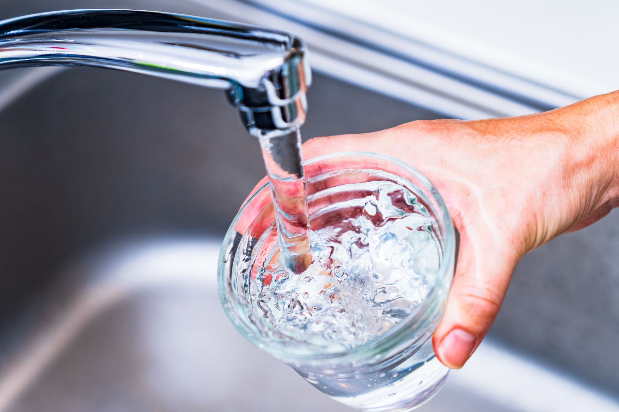 Henkilö täyttämässä vesilasia hanavedellä.