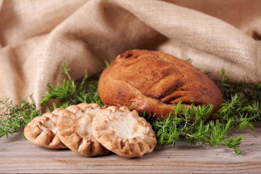 Pöydällä on kangasliina, karjalanpiirakoita ja kalakukko.