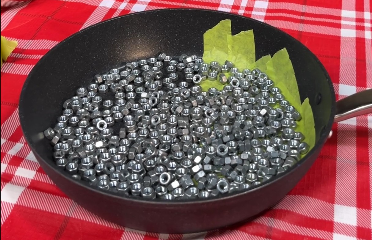 Paistinpannu, jonka pinta on puoliksi teipattu ja jonka päällä on muttereita.