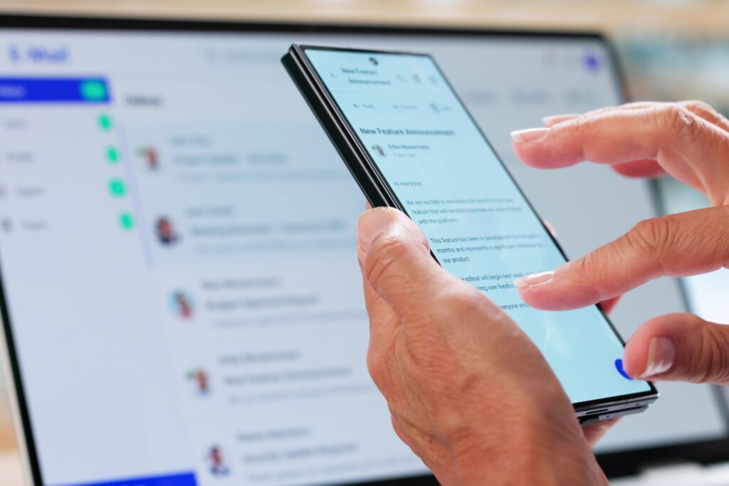 Henkilö käyttämässä puhelinta ja tietokonetta.