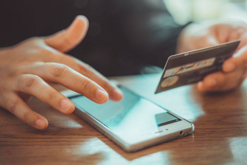 Henkilö, puhelin ja maksukortti.