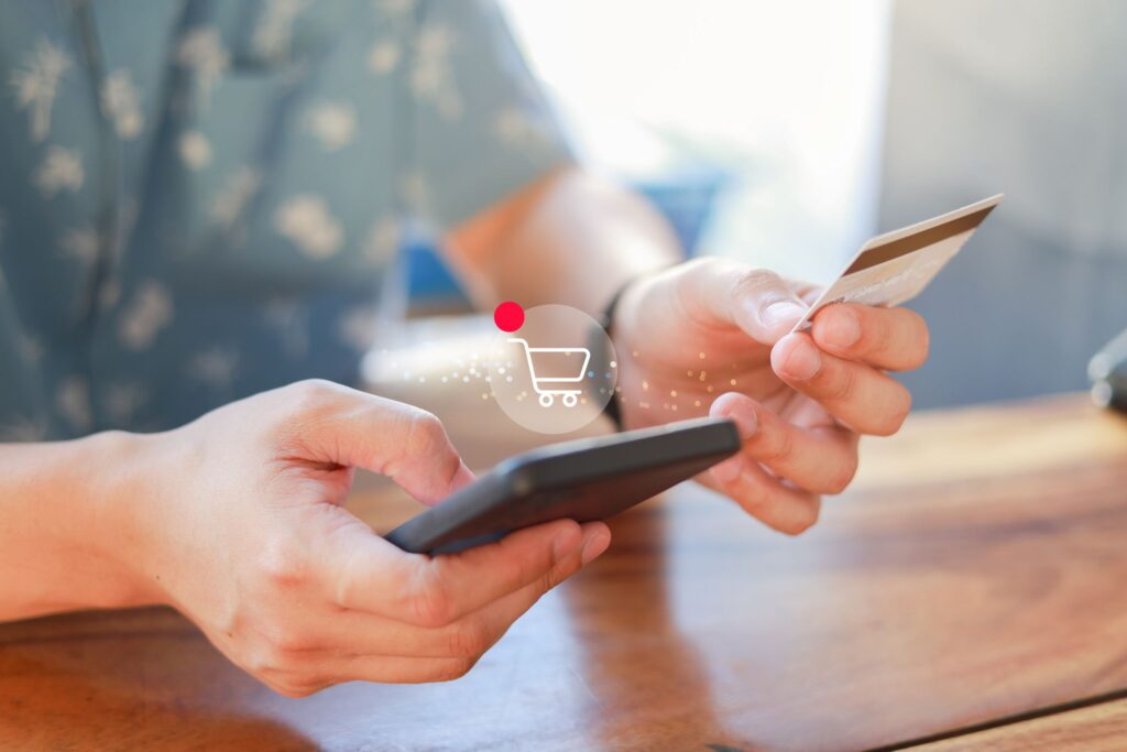 Henkilöllä on kädessään puhelin ja pankkikortti.