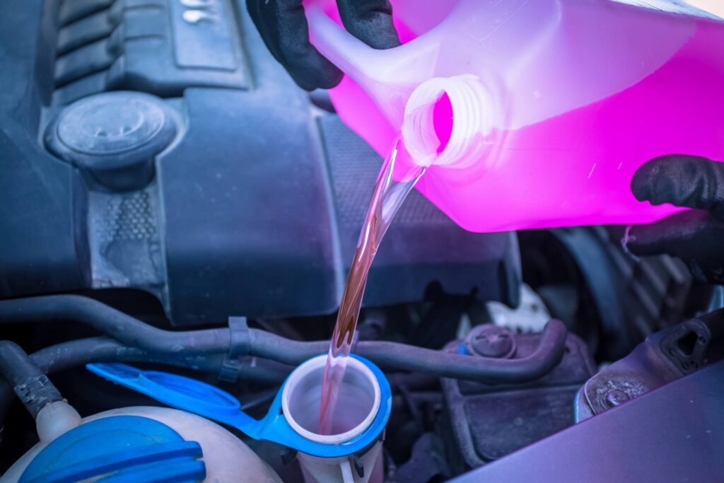 Henkilö kaatamassa lasinpesunestettä säiliöön.