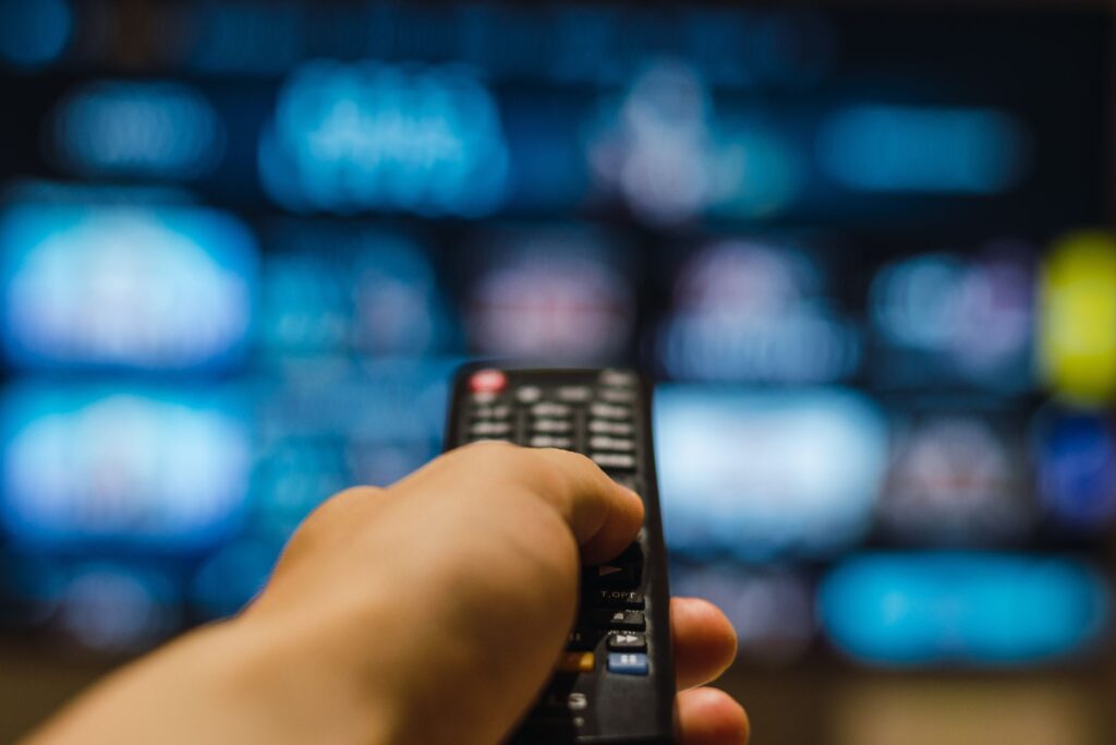 Henkilöllä on kädessään television kaukosäädin.